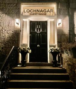 a black front door of a guest house with stairs at Lochnagar Guest House in Aberdeen