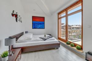 a white bedroom with a bed and a window at Grand Apartments - Neptun Park. in Gdańsk