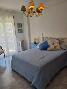 a bedroom with a bed with blue pillows and a chandelier at COSTA DAURADA APARTAMENTS - 174 Formentor Luxe II in Salou