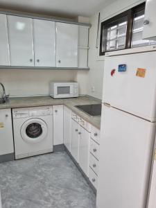 a white kitchen with a refrigerator and a microwave at COSTA DAURADA APARTAMENTS - 174 Formentor Luxe II in Salou