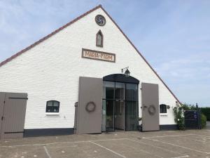 - un grand bâtiment blanc avec un panneau dans l'établissement Mariafarm, à Zevenbergen
