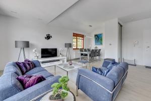 a living room with a blue couch and a tv at Grand Apartments - Neptun Park Escala Seaside Apartment in Gdańsk