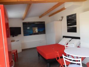 a room with a table and a bed and a tv at Nuit calme sur domaine in Calcatoggio