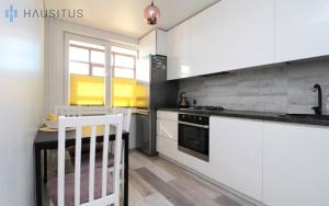 a kitchen with white cabinets and a sink and a stove at Nemuno apartamentai in Panevėžys