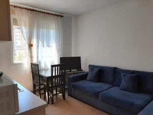 een woonkamer met een blauwe bank en een tafel bij Sazani's Place in Fier
