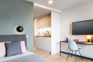 a bedroom with a bed and a desk and a kitchen at ipartment Böblingen Region Stuttgart in Böblingen