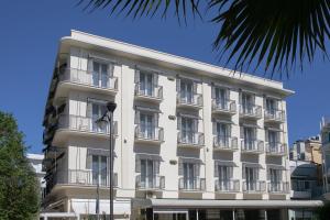un edificio bianco con balconi e una palma di Hotel Gambrinus Mare a Cattolica