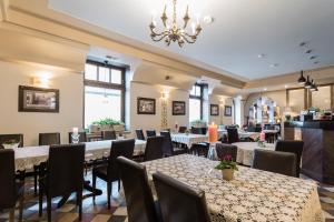 a restaurant with tables and chairs and a chandelier at Hotel Ester in Kraków