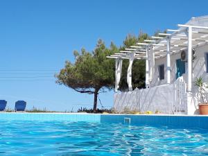 a swimming pool in front of a house with a tree at Bellevue Village ''Αdults Only'' in Agia Pelagia
