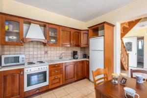 a kitchen with wooden cabinets and a white refrigerator at Apollo Villa in Kolymbia