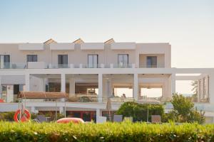 a large white building with tables and chairs in front of it at Sunny View Hotel in Kardamaina