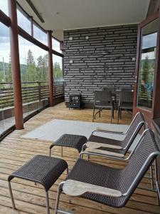 Un balcón con sillas, mesas y una pared de ladrillo. en Tahko Spa Suite B3 en Tahkovuori