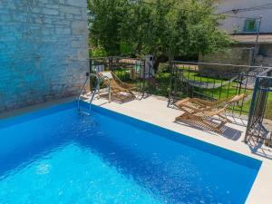- une piscine bleue avec 2 chaises à côté dans l'établissement Holiday Home Toni by Interhome, à Svetvinčenat