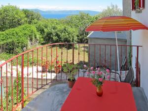 a red table with an umbrella on a balcony at Apartment Adalgisa - LBN128 by Interhome in Labin
