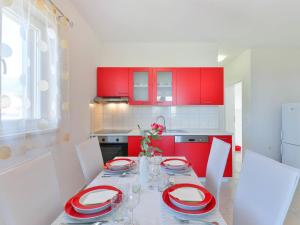a kitchen with red cabinets and a table with red plates at Apartment Matas-2 by Interhome in Rovanjska