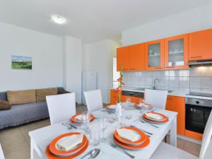 una cocina con una mesa blanca con armarios naranjas en Apartment Matas - SRD318 by Interhome en Rovanjska