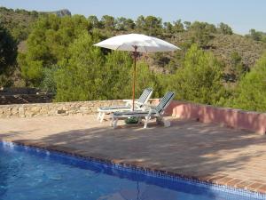 a pair of chairs and an umbrella next to a swimming pool at Holiday Home De la Cruz by Interhome in Aledo