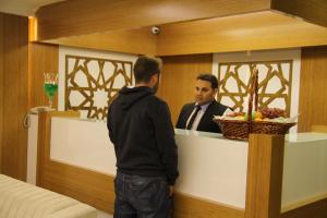 a man standing at a counter with a man in a mirror at Besiktas Otel in Istanbul
