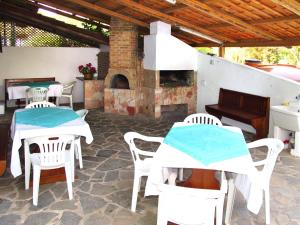 eine Terrasse mit weißen Tischen und Stühlen sowie einem Kamin in der Unterkunft Holiday Home Villa Margherita by Interhome in Platamona