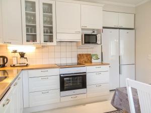 a white kitchen with white cabinets and a refrigerator at Holiday Home Villa einola by Interhome in Nilsiä