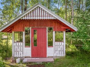 un pequeño cobertizo con una puerta roja en el bosque en Holiday Home Koivuranta by Interhome, en Räätäniemi