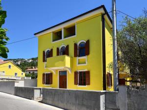 ein gelbes Haus mit roten Fenstern auf einer Straße in der Unterkunft Apartment Val-1 by Interhome in Sveti Juraj