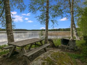 a picnic table in front of a lake at Holiday Home Rantapelto by Interhome in Heinälahti