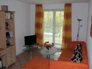 a living room with an orange couch and a television at Apartment Gollwitzer Park - Insel Poel-1 by Interhome in Gollwitz