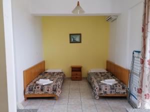 two beds in a room with yellow walls at Andreas Apartments in Kefalos