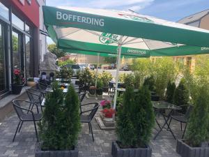 d'une terrasse avec des tables, des chaises et un parasol. dans l'établissement Sanhe, à Rollingen