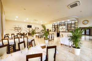 a restaurant with white tables and chairs and plants at ROYAL M in Sabinov