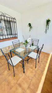 szklany stół z 2 krzesłami i stół z kwiatami w obiekcie Chalet en primera Línea con 150m2 de Jardín Privado w mieście Torrox Costa
