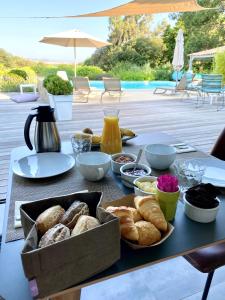 a table with a tray of bread and other food at Villa Limone, maison d'hôtes in Calenzana