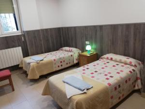 a room with three beds and a table with a lamp at Pensión Agarimo in Trapagaran
