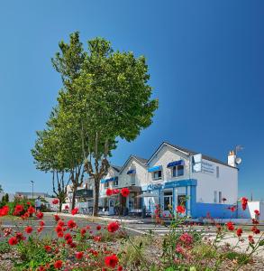 ein großes weißes Gebäude mit einem Baum und roten Blumen in der Unterkunft Hotel Restaurant L'Atlantique in Saint-Jean-de-Monts