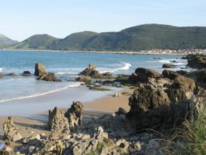 a beach with rocks and the ocean and mountains at Residencial Cilla - 6022 in Noja