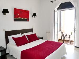 a bedroom with a large bed with red pillows at Hotel Cubata in Nazaré