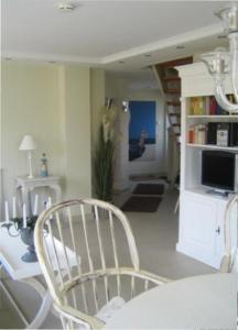 a living room with a white chair and a television at Landhaus Glowe in Glowe