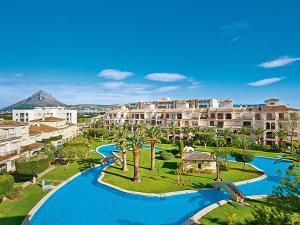 a resort with a pool and palm trees and buildings at BUNGALOW LA ISLA in Jávea
