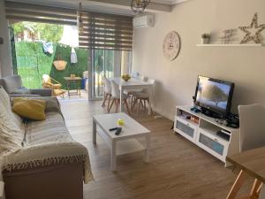 a living room with a couch and a tv and a table at BUNGALOW LA ISLA in Jávea