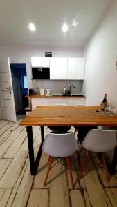 a kitchen with a wooden table and two white chairs at Apartament Piasek i Morze in Rowy