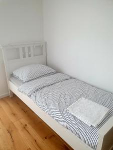 a white bed in a room with a wooden floor at Apartament Piasek i Morze in Rowy