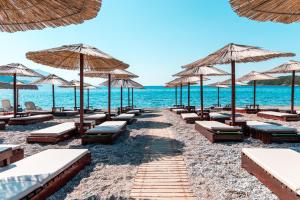 a row of beach chairs and umbrellas on a beach at Apartments Horizont in Budva