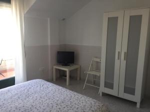 ポルトノボにあるApartamentos Playa Portonovoのベッドルーム(ベッド1台、テレビ、椅子付)