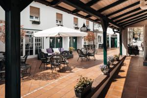 a patio with a table and chairs and an umbrella at Hotel Freihof am Roland in Wedel