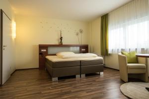 a bedroom with a bed and a chair and a window at Hotel Viola in Hochheim am Main