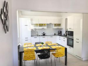eine Küche mit einem Esstisch und gelben Stühlen in der Unterkunft Appartement Le Solea 100m2 climatisé parking proche Sanctuaires in Lourdes