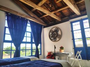1 dormitorio con cortinas azules, 1 cama y escritorio en Albergue Casa de los Hidalgos - Sólo para Peregrinos, en Hospital de Órbigo