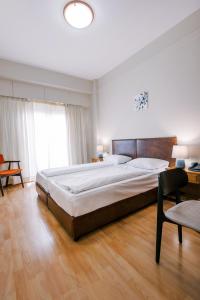 a bedroom with a large bed and a chair at Hotel Cronos in Arta