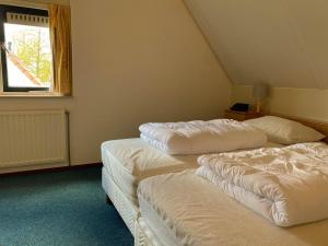 two white beds in a room with a window at Hello Zeeland - Vakantiehuis Stern 265 in Breskens